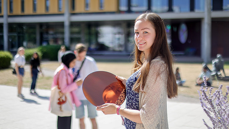 Das Bild zeigt eine Studentin der Uni Magdeburg mit einem Wafer.